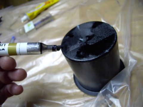1978 Ford Bronco - A marker is used to write on a black cylindrical object, possibly a car part, with other items in the background.