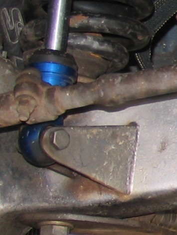 1984 Ford Bronco - This image shows a close-up of a vehicle's suspension system, focusing on a blue bushing and linkage.