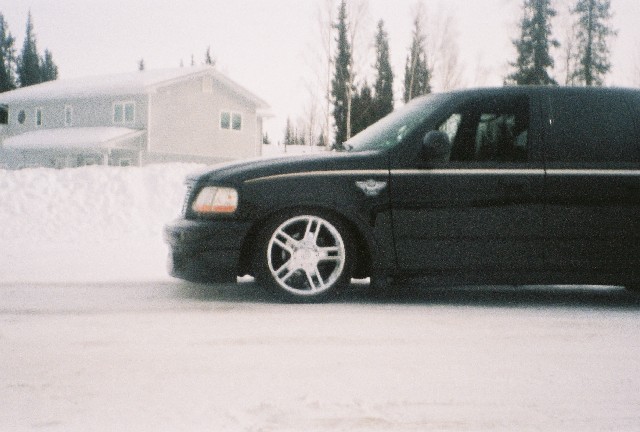 Lowered black Ford F-150 with Harley-Davidson badge and chrome wheels on snow