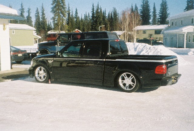 Black lowered Ford F-150 crew cab pickup on snow with chrome wheels