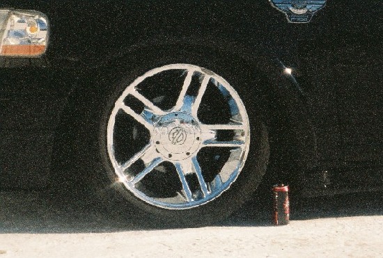 Chrome split-spoke wheel on a dark vehicle photographed at night