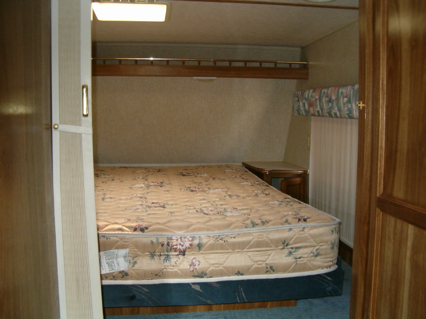 Camper bedroom with floral bedspread and wooden trim