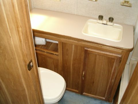 1985 Ford Bronco - Interior view of a compact RV bathroom a toilet and sink vanity.
