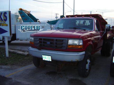 1992 Ford Bronco - Front view of a red dump truck parked next to a tow truck.