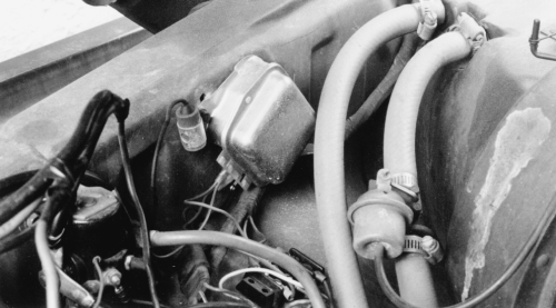 Black-and-white photo of an under-hood electrical component with wiring and hoses