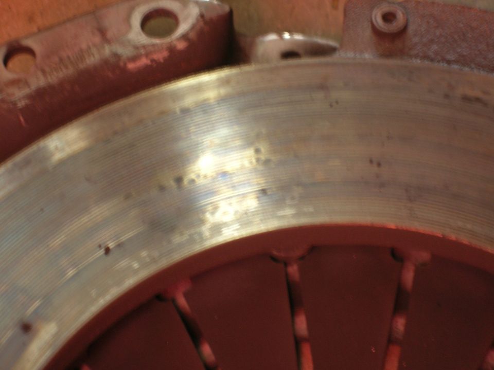 Close-up of a worn clutch disc with a red pressure plate visible