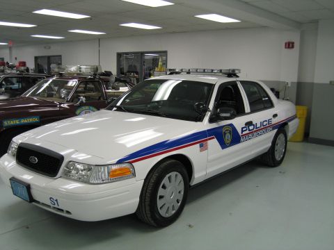 1991 Ford LTD Crown Victoria - white Ford Crown Victoria police cruiser marked 'POLICE MARLBOROUGH' with blue and red striping, parked in a showroom.