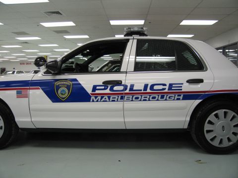 1991 Ford LTD Crown Victoria - Side profile of a white Ford police cruiser with large 'POLICE MARLBOROUGH' lettering, blue and red stripes and a roof light bar.