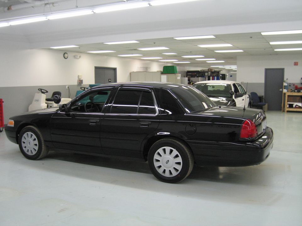 Side and rear view of black Ford Crown Victoria sedan in a shop