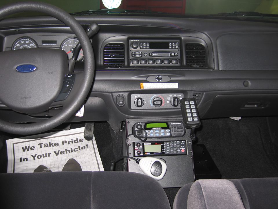 Ford dashboard with mounted radios and a We Take Pride sign on the seat