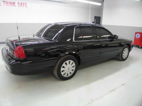 1991 Ford LTD Crown Victoria - Rear three-quarter view of a black Ford sedan with steel wheels parked on a polished floor in front of a wall reading THINK SAFE.