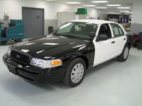1991 Ford LTD Crown Victoria - Front three-quarter view of a black-and-white Ford sedan with paper in the windshield, parked in a tidy workshop.