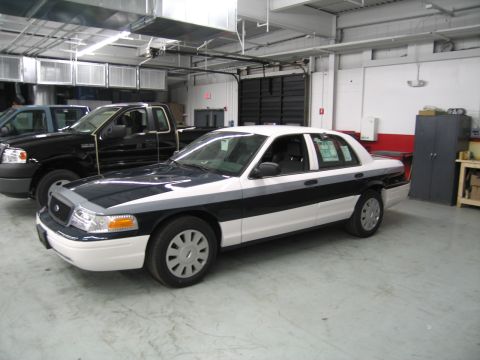 1991 Ford LTD Crown Victoria - Front three-quarter view of a black-and-white Ford sedan with a door open, parked beside a black pickup in a garage.