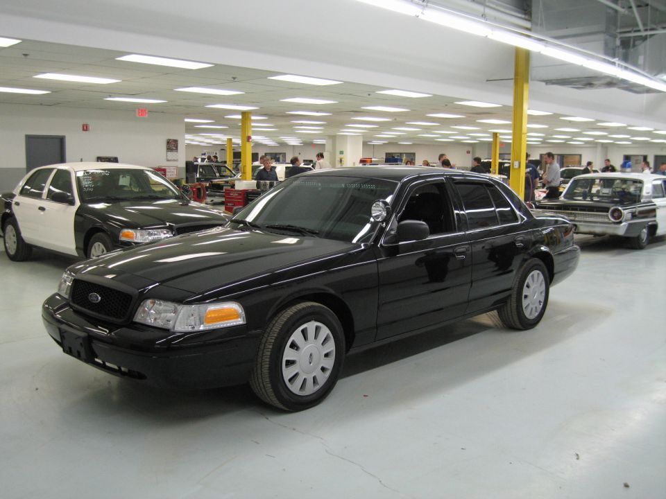 Black Ford Crown Victoria sedan front quarter view in a large workshop