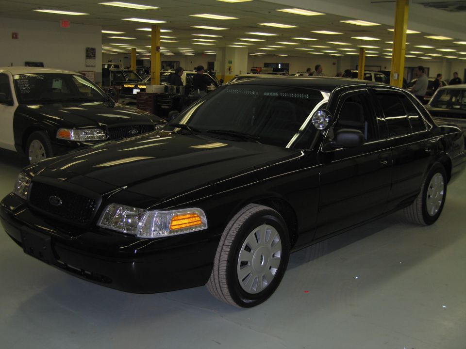 Black Ford Crown Victoria sedan with spotlight, front quarter in a workshop