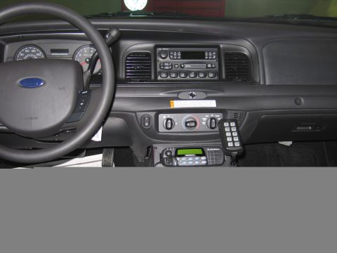 1991 Ford LTD Crown Victoria - Ford police car dashboard shows the steering wheel, factory radio, climate controls and a console-mounted two-way radio with keypad.