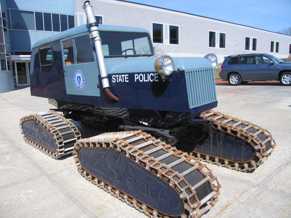 Three-quarter front view of blue STATE POLICE tracked snow vehicle on pavement