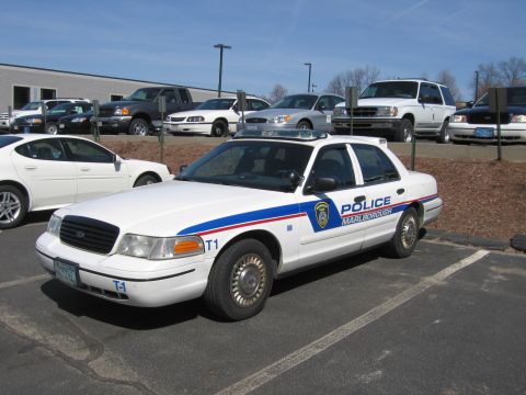 1991 Ford LTD Crown Victoria - white Ford Crown Victoria police cruiser marked POLICE MARLBOROUGH with a roof light bar sits in a parking lot among other vehicles.