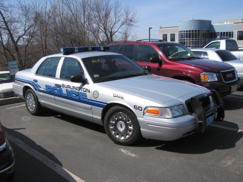 1991 Ford LTD Crown Victoria - silver Ford Crown Victoria marked BURLINGTON POLICE and DARE sits in a parking lot with a red SUV alongside.