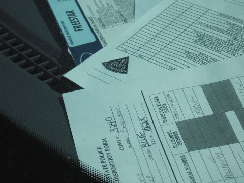 1991 Ford LTD Crown Victoria - Handwritten State Police vehicle disposition forms and a FREESTAR document rest on a dark dashboard behind a windshield.