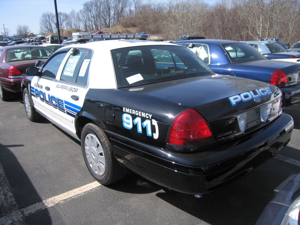 Rear three-quarter view of black and white police Ford sedan marked 911