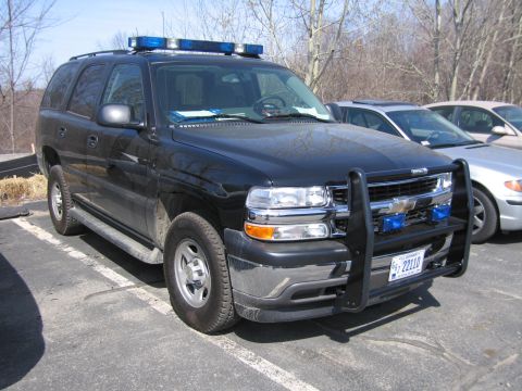 1991 Ford LTD Crown Victoria - black Chevrolet Tahoe police SUV with chrome brush guard, blue light bar and 22110 plate, parked in a paved lot.