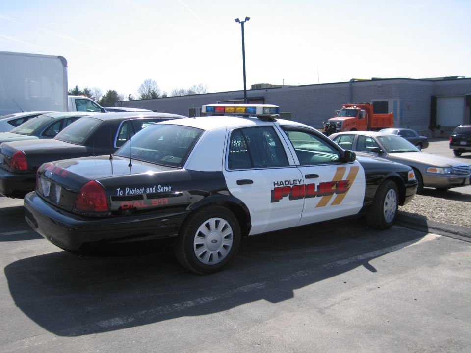 Black and white Hadley Police Ford sedan, rear three-quarter view