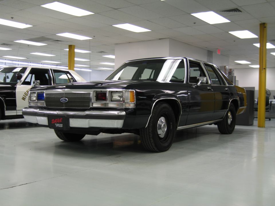 Front three-quarter view of black vintage Ford sedan with DARE plate