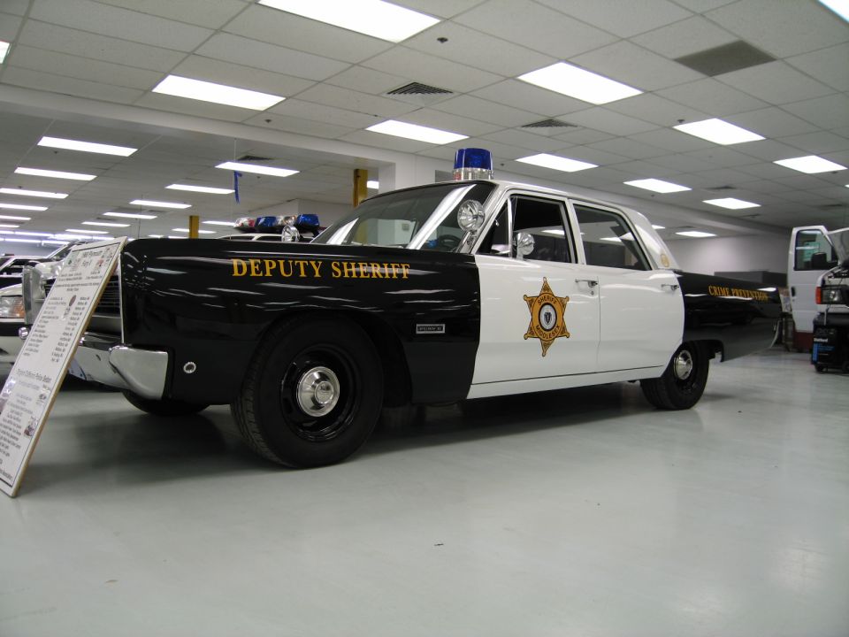 Black-and-white Deputy Sheriff sedan with blue roof light indoors