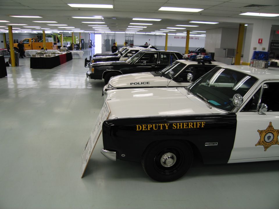 Line of police cars led by a black-and-white Deputy Sheriff sedan indoors