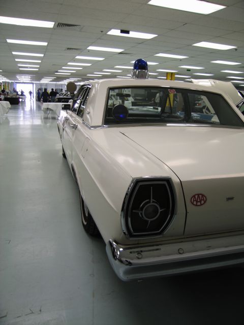 1991 Ford LTD Crown Victoria - white 1960s Ford sedan displayed indoors, fitted with a blue roof dome light and a red AAA emblem on the rear fender.