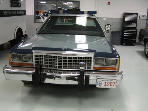1991 Ford LTD Crown Victoria - Head-on view of a two-tone blue police sedan with a roof light bar, spotlight and a Massachusetts 1987 license plate.
