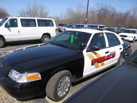 1991 Ford LTD Crown Victoria - black-and-white Ford Crown Victoria marked Hadley Police with a roof light bar, parked outdoors near a white van.