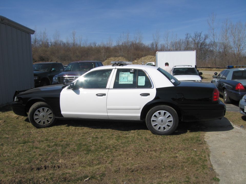 Side profile of black and white Ford Crown Victoria police sedan outdoors