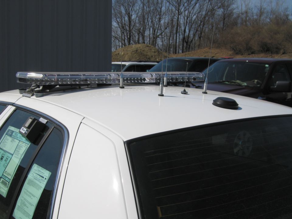 Close-up of police car roof with chrome light bar and antennas outdoors