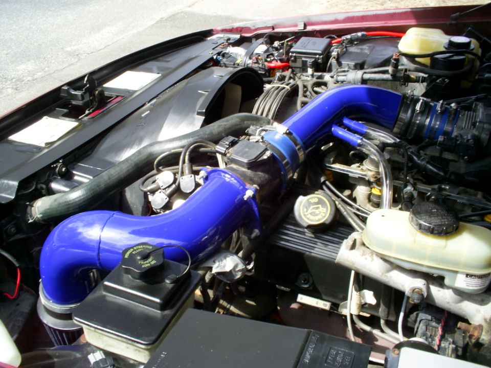 Engine bay with blue intake piping and a 1995 Ford Crown Victoria badge