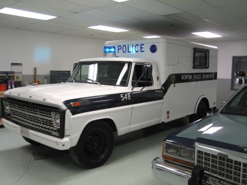1991 Ford LTD Crown Victoria - white vintage Ford F-series Newton Police Department utility truck numbered 548 with a box rescue body and roof lightbar displayed indoors.