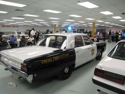 1991 Ford LTD Crown Victoria - Black-and-white sedan lettered Crime Prevention with a sheriff star and single blue roof beacon, parked in an indoor collection.