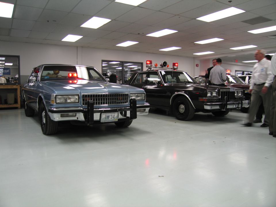 Silver Chevrolet Caprice and black patrol sedan with people indoors