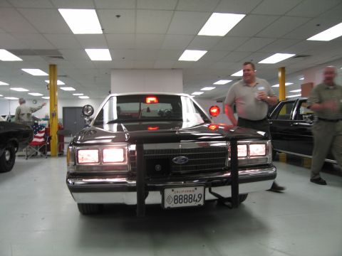1991 Ford LTD Crown Victoria - Front view of a black Ford patrol sedan with chrome push bar, lit headlights and a California plate reading 888849.