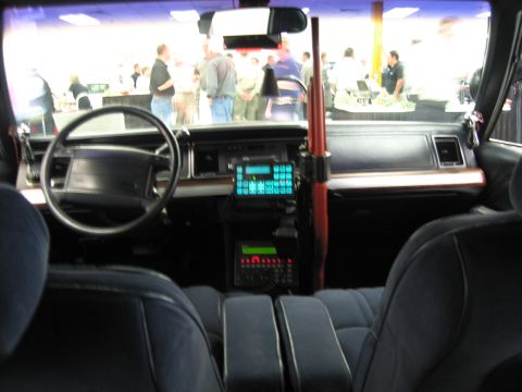 1991 Ford LTD Crown Victoria - Interior of a police car showing the steering wheel, dash-mounted radio keypad and a vertical shotgun mount between the seats.