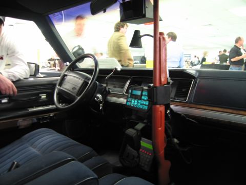 1991 Ford LTD Crown Victoria - Police cruiser interior with blue bench seat, dash radio keypad, handheld mic and a red vertical shotgun mount.