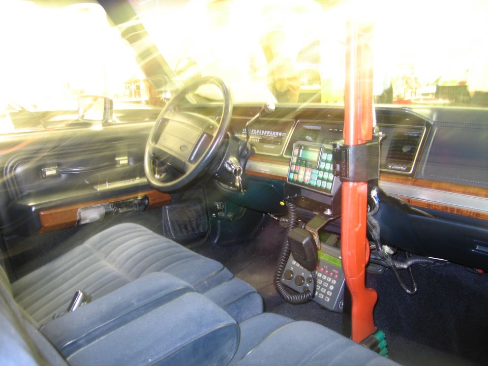 Police car cabin with steering wheel, radio keypad, mic and red shotgun mount