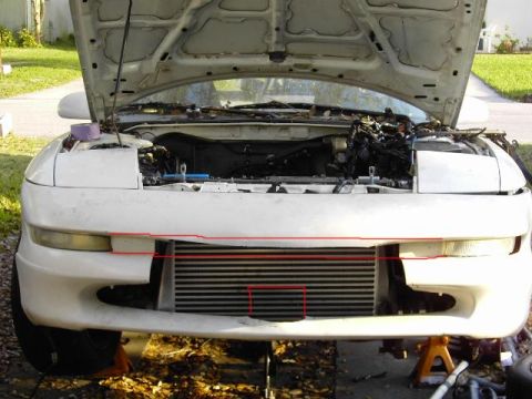 1996 Ford Probe - The front end of a white vehicle is shown with the hood open, revealing the engine bay and an intercooler.