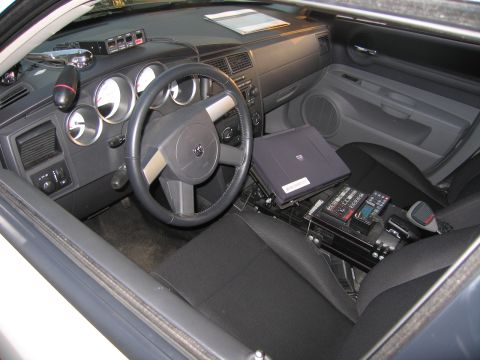 1991 Ford LTD Crown Victoria - Police vehicle interior showing the steering wheel, instrument gauges, and a mounted laptop computer with control console on the center flo…