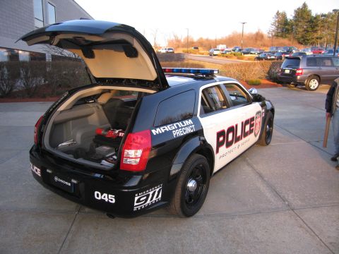 1991 Ford LTD Crown Victoria - Rear three-quarter view of a black and white police Dodge Magnum wagon, unit 045, with its liftgate raised and roof light bar.