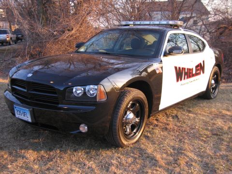 1991 Ford LTD Crown Victoria - Front three-quarter view of a black Dodge Charger with WHELEN livery, roof light bar, and a Connecticut plate reading 235 UFL.