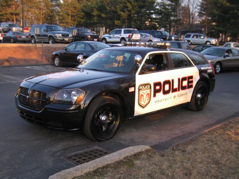 1991 Ford LTD Crown Victoria - Front three-quarter view of a black and white police Dodge Magnum wagon lettered POLICE Protect & Serve with a roof light bar in a parking…