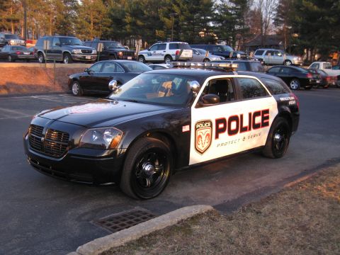 1991 Ford LTD Crown Victoria - Front three-quarter view of a black and white police Dodge Magnum wagon marked POLICE Protect & Serve with roof light bar parked in a lot.