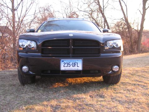 1991 Ford LTD Crown Victoria - Head-on front view of a black Dodge Charger with a roof light bar, lit headlights, and a Connecticut plate reading 235 UFL on a grassy fiel…